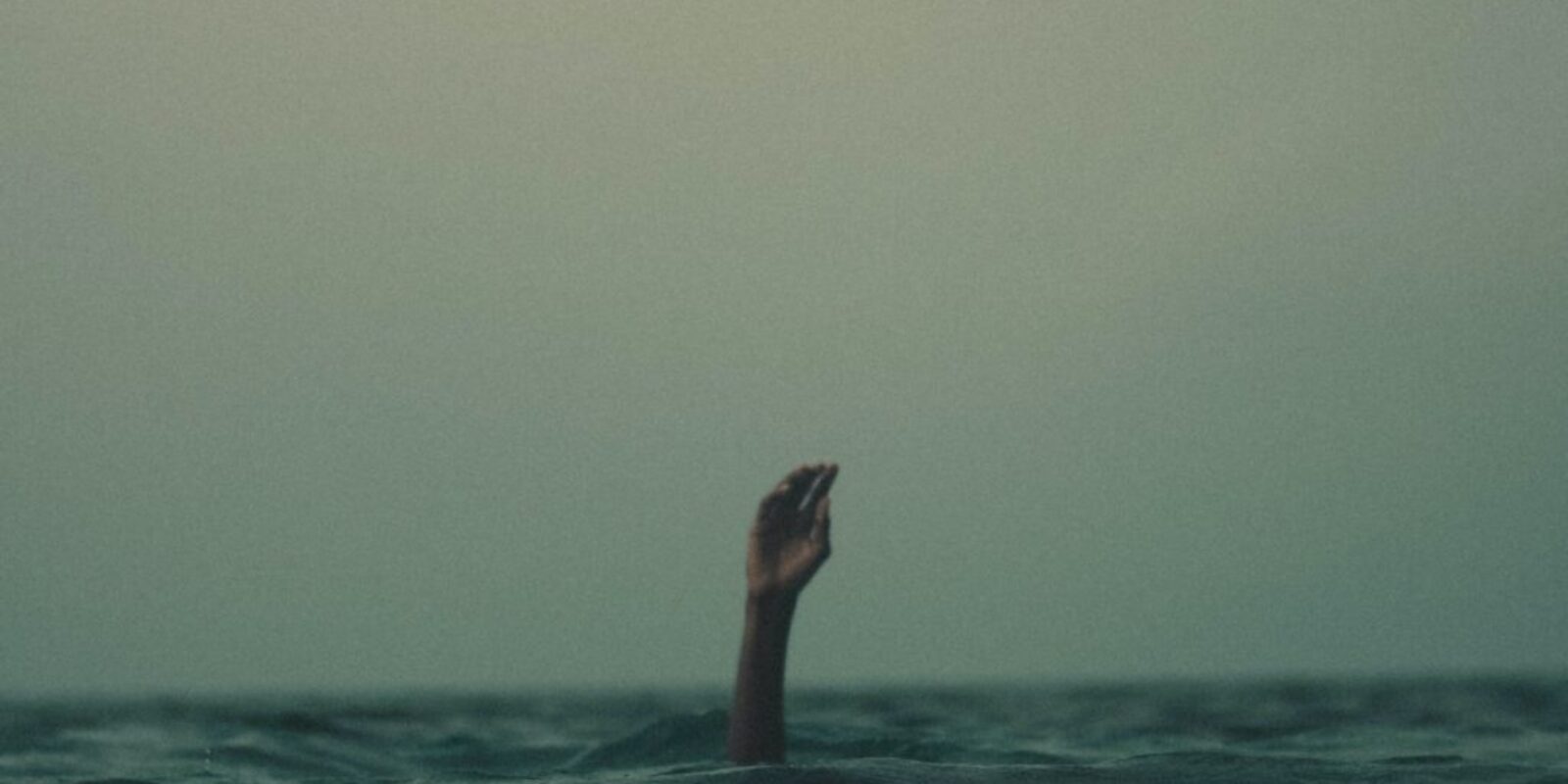 person with hand above water